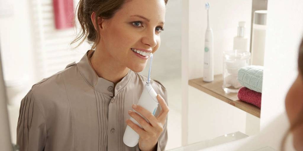 Mujer en el espejo con irrigador dental