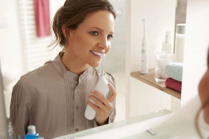 Mujer en el espejo con irrigador dental